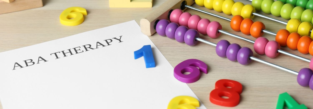 Image of a table with an abacus, number toys, and a paper that reads "ABA Therapy"