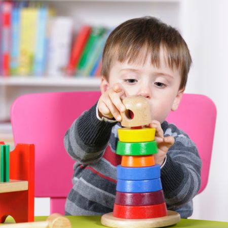 A toddler boy stacking colorful blocks