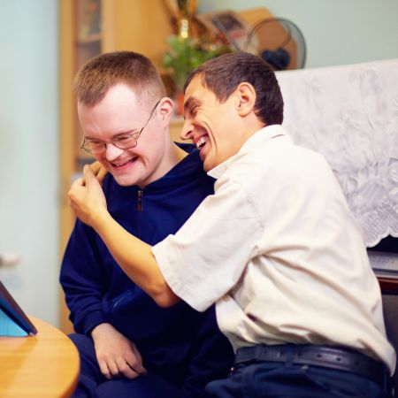 Two developmentally disabled men laugh together at home