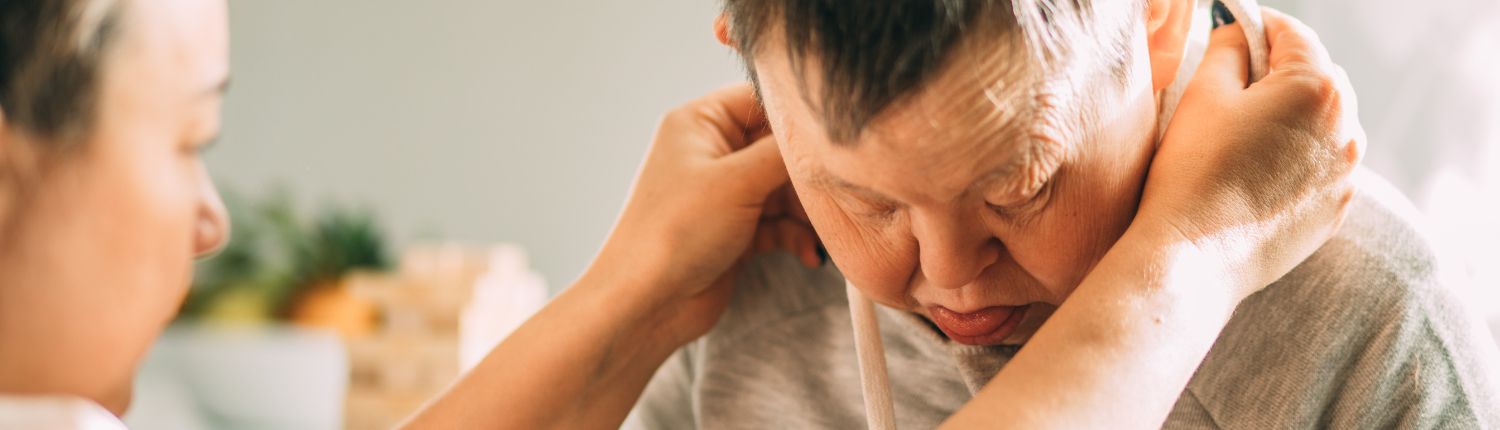 residential_1500x430 Woman helps disabled man put his sweatshirt hood on