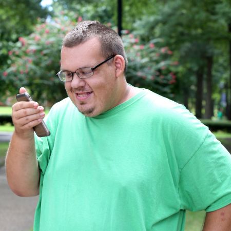 An intellectually disabled man smiling and talking on cell phone outside