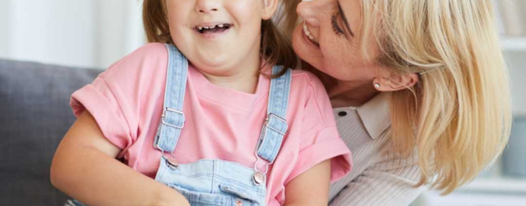 Young girl giggling and hugging her helper at home