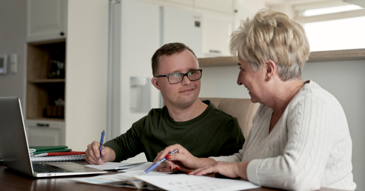 adult with special needs with family member working on paperwork at the kitchen table