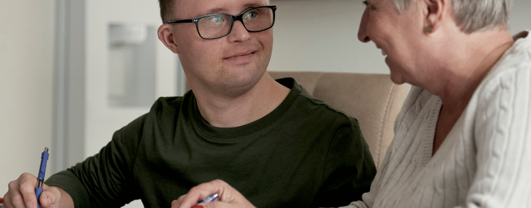 adult with special needs with family member working on paperwork at the kitchen table