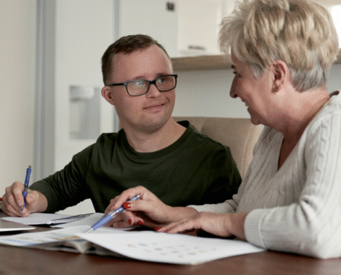adult with special needs with family member working on paperwork at the kitchen table