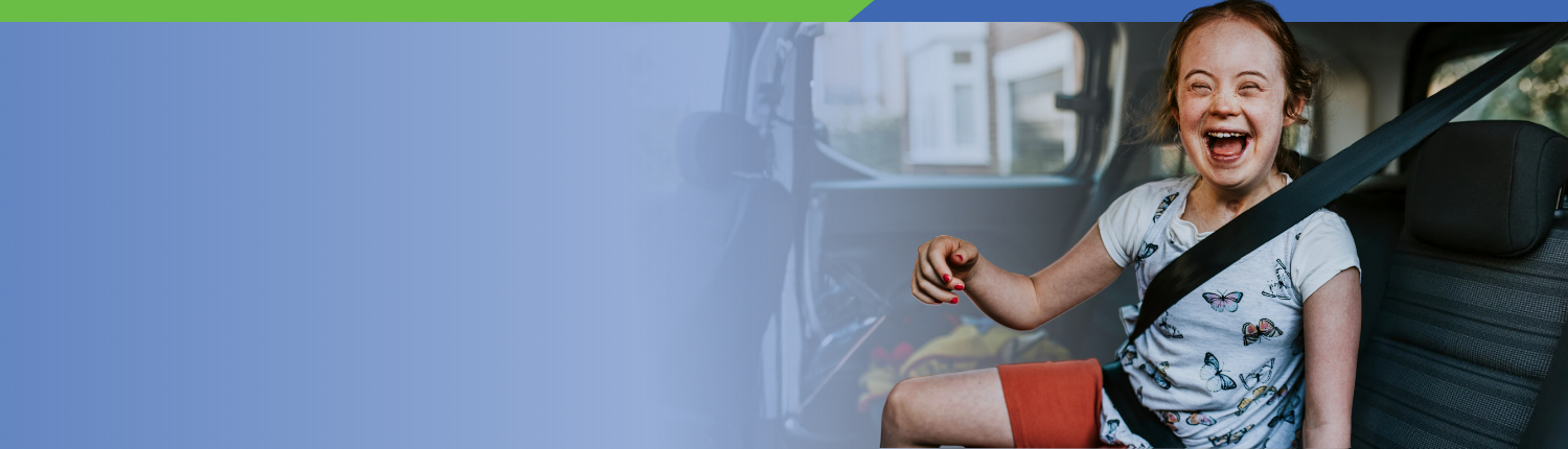 tween girl with down syndrome smiling and very happy wearing a butterfly tee shirt and seat buckled into a vehicle