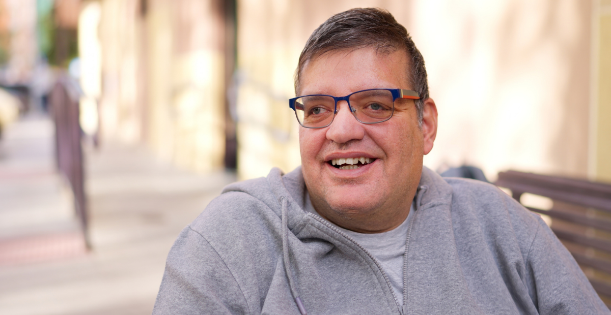 adult man with glasses and a gray sweatshirt smiling