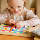 preschool aged girl with Down Syndrome smiling and working on a skills buttoning book at home